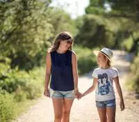Une mère et sa fille marchent sur un sentier proche des vignes