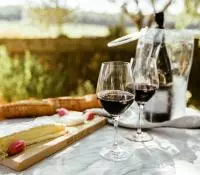 Verres de vin rouge et planche de fromages servis sur une table à l'extérieur