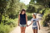 Une mère et sa fille marchent sur un sentier proche des vignes