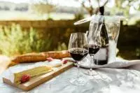 Verres de vin rouge et planche de fromages servis sur une table à l'extérieur